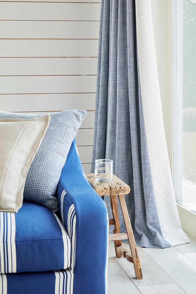 detalle de brazo de sofá tapizado en tono azul liso y azul con rayas
