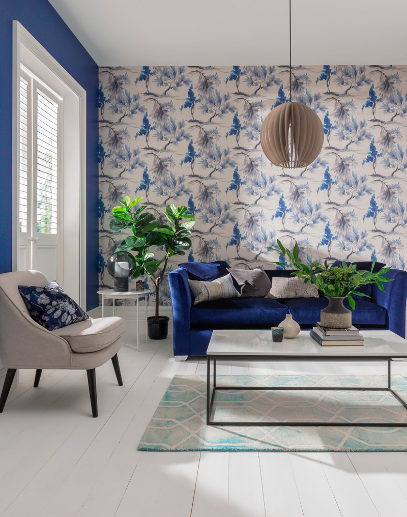 salón con papel pintado  vegetal, sofá, butacas y cojines a juego en tonos natural, beige y azules