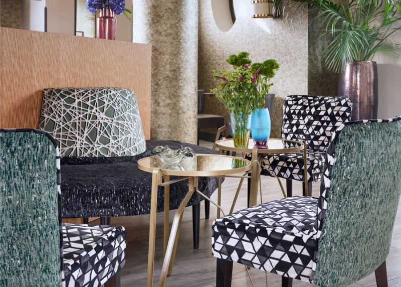hall de hotel con sillas tapizadas con las telas de tapicería urbana fr, jacquard geométrico y falsos lisos en tonos azules y verdes