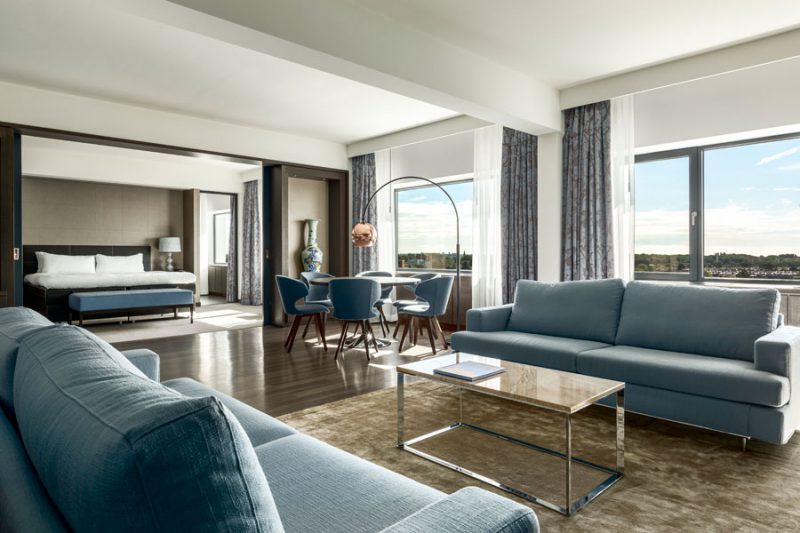 suite del hotel Marriot donde pueden verse cortinas, moqueta, cabecero de cama, puff, sillas y sofá tapizados con tejidos de ganceedo