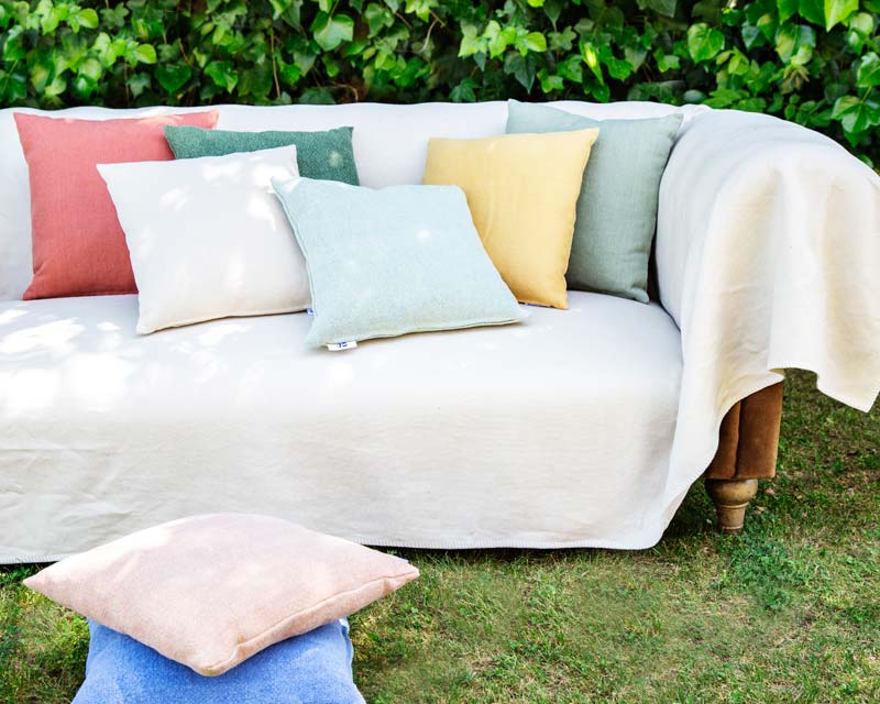 cojines de colores empolvados en un sofá de exterior para jardin