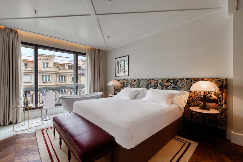 habitación con cabecero de cama taapizado con una tela con motivos vegetales de William Morris y alfombra de Gancedo en elHotel Bless de Madrid