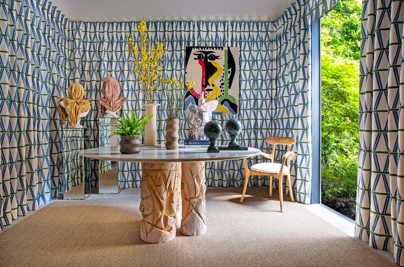 corner de gancedo compuesto por cortinaje geométrico en las paredes, moqueta de yute, sillas tapizadas y mesa central
