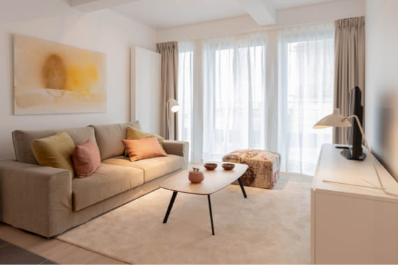 salón del apartamento con sofá, butaca y cortinas