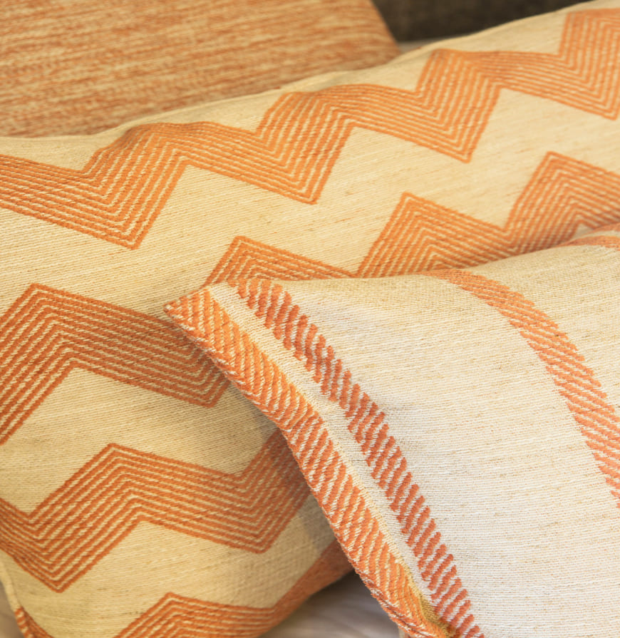 detalle de cojines con tela geométrica en tonos anaranjados