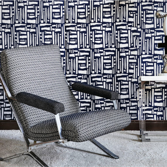 butaca tapizada con una tela de textura blanca y pared entelada con diseño geométrico negro y blanco