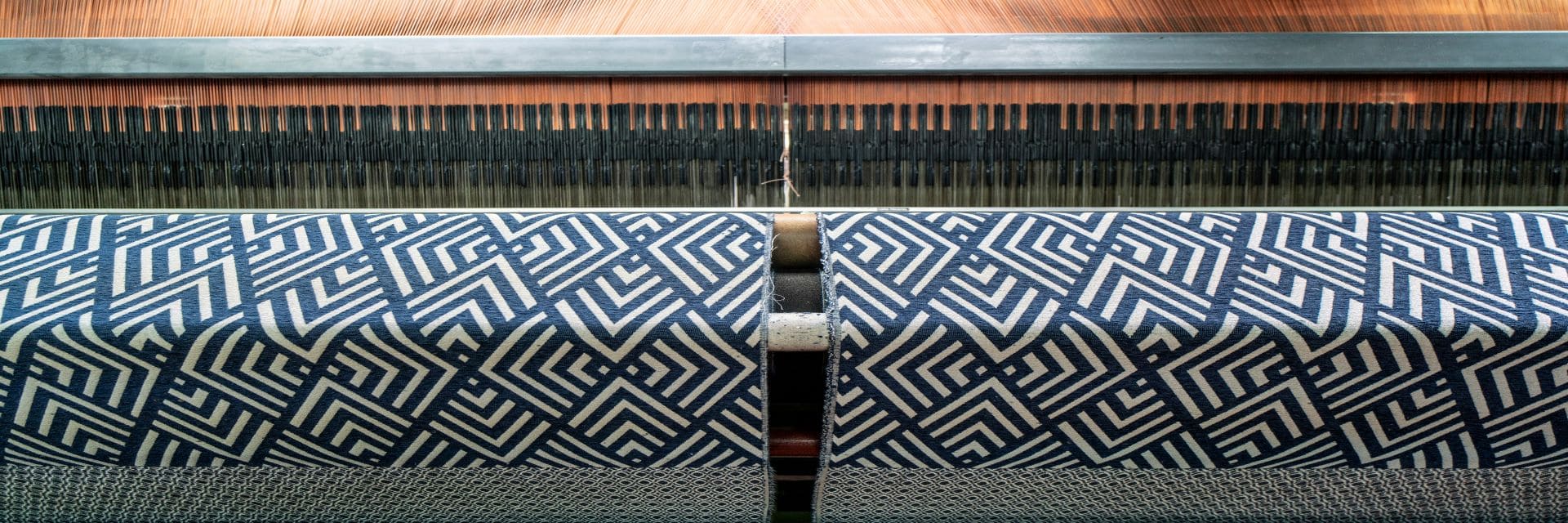 telar de fabrica tejiendo una tela jackard geometrica en tono azul y blanco