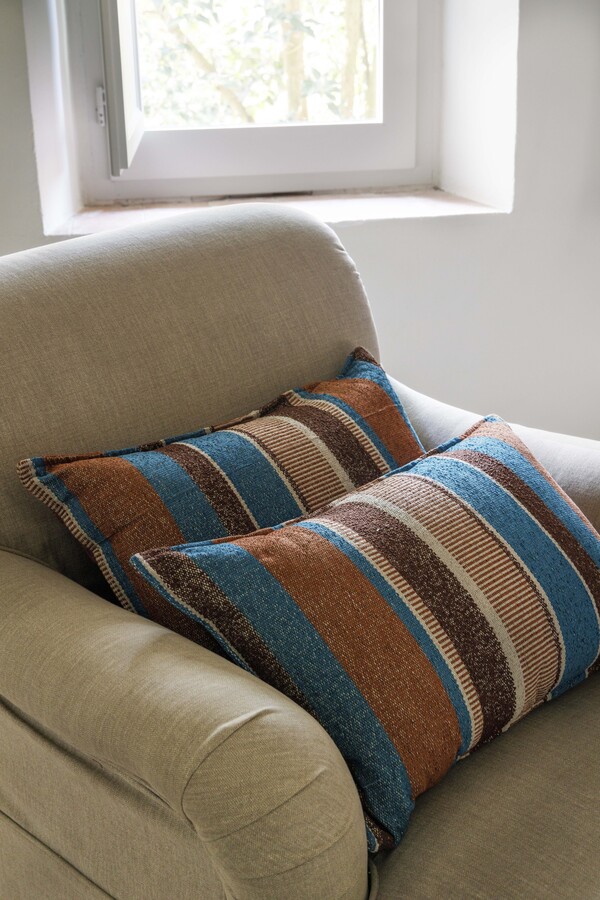 sillón con cojines en colores azules y terrosos.