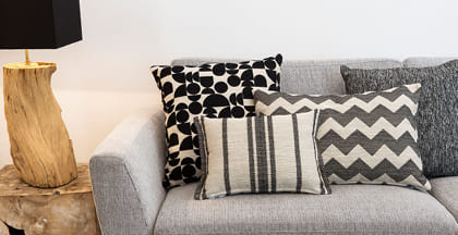 cojines con telas jacquard de chenilla en diseño geométrico y sillón tapizado en tono gris