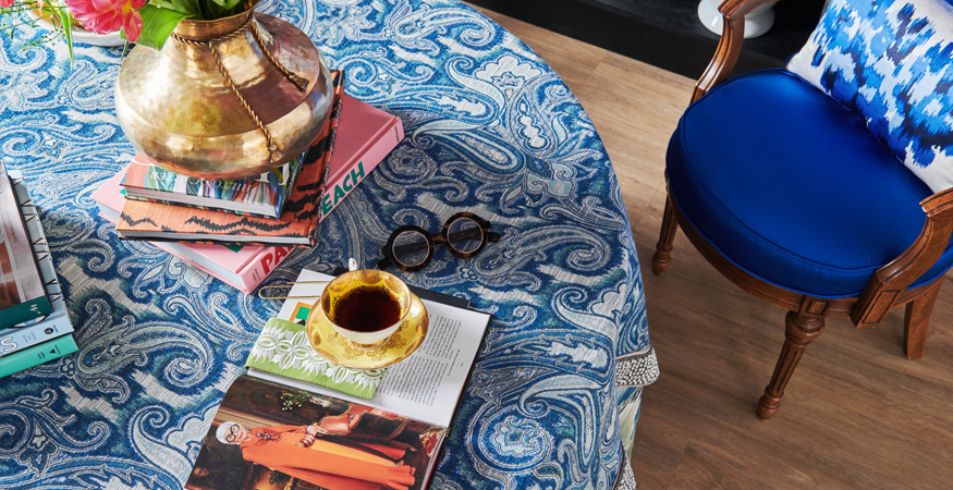 detalle de tejido con motivos abstractos en tono azul sobre mesa redonda y silla tapizada en azul liso