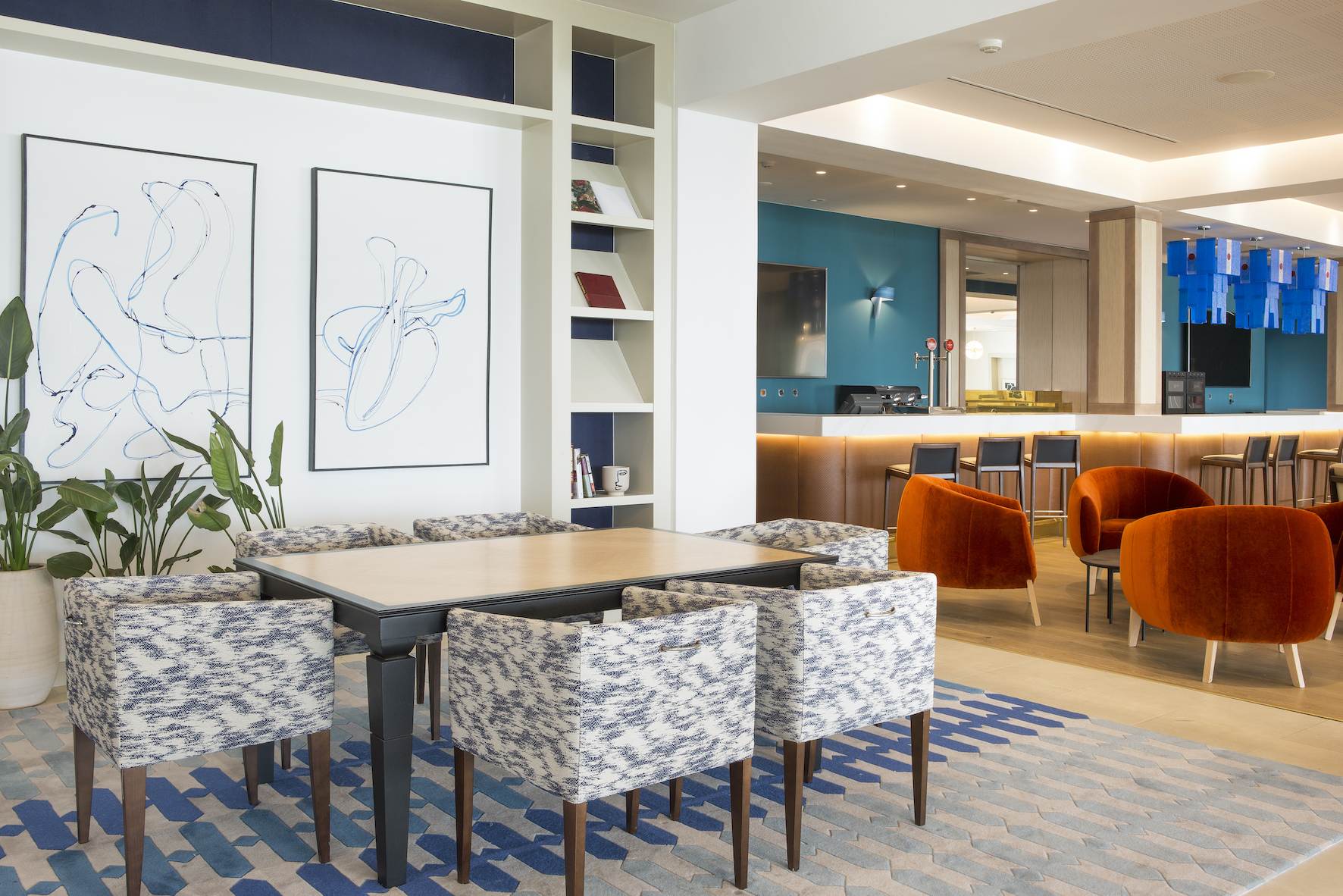 restaurante de hotel con alfombra geométrica en tonos azules y butacas tapizadas con tejidos jaspeados y terciopelo