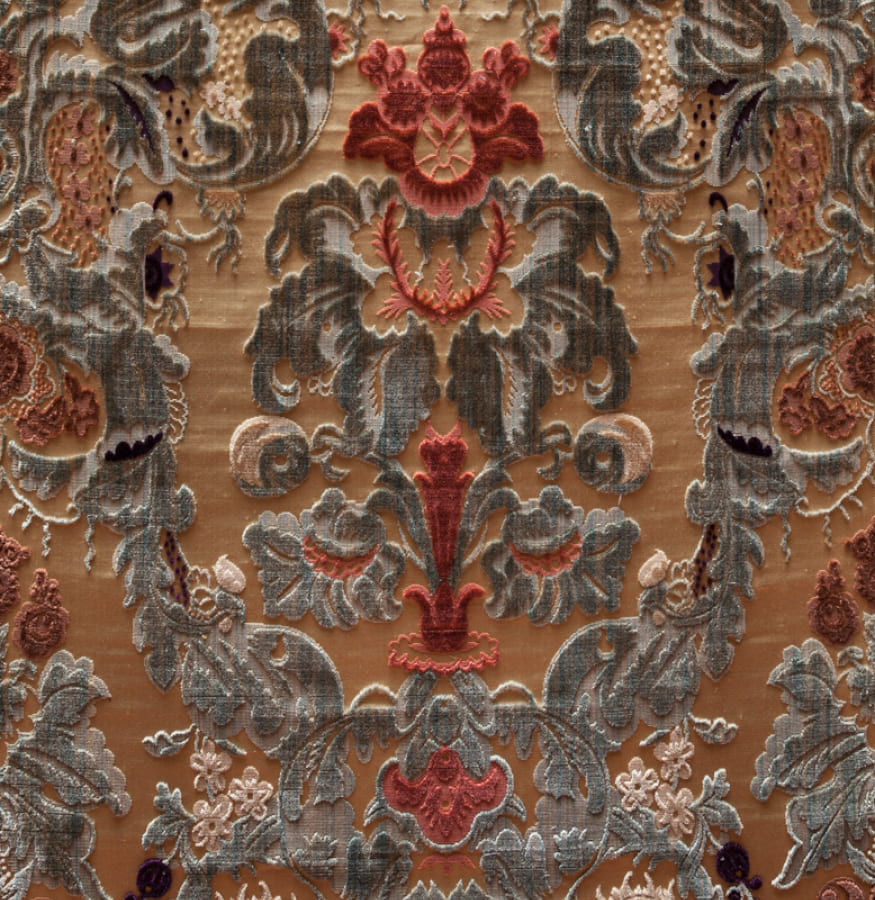 detalle de tejido de jacquard con motivos florales en tonos anaranjados, caldero y grises