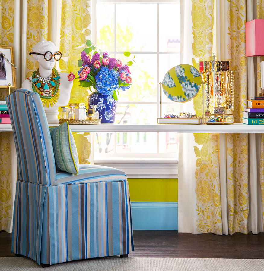 tocador con silla tapizada de rayas azules y cortinas con estampado floral en tono amarillo