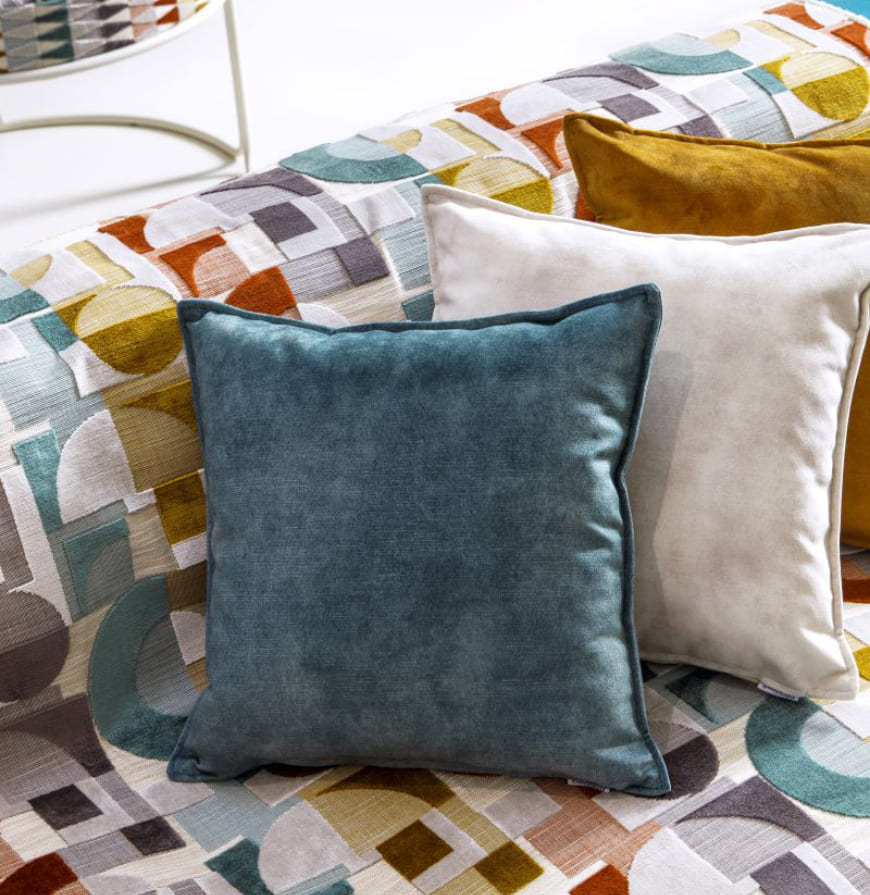 tela geométrica multi color en un sofá con cojines de chenilla lisos multi color