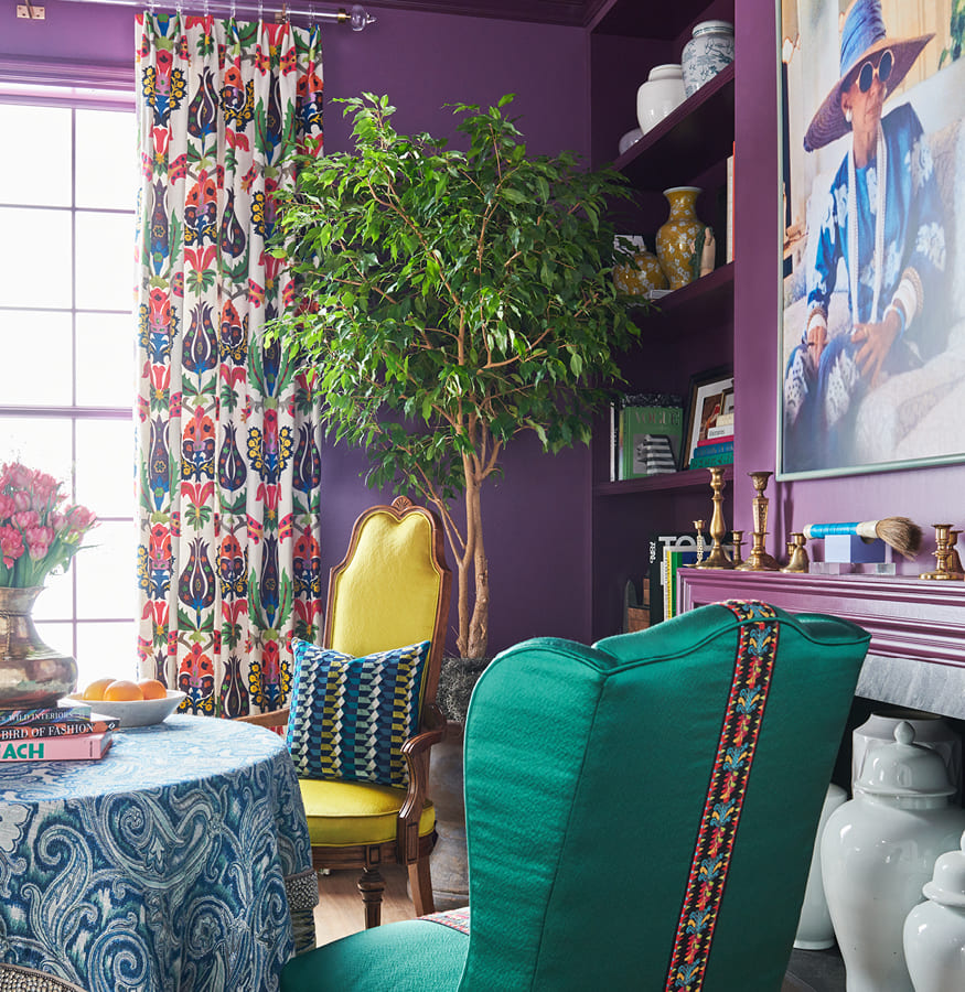 habitación con sillones tapizados con pasamanería y telas lisas, mesa redonda con mantel abstracto y cortinas florales multicolores de la coleccion de Iris Apbel