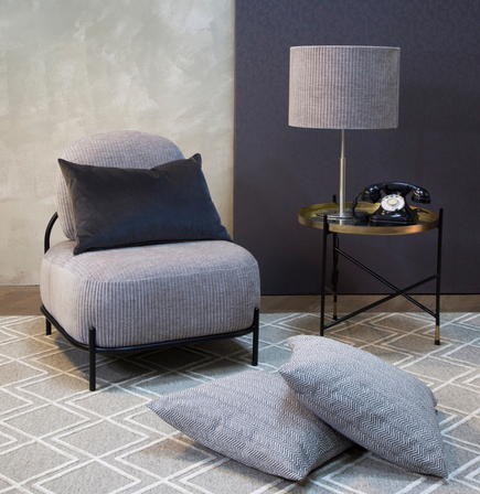 zona de salón con butaca tapizada en jacquard gris, alfombra geométrica en tonos grises y pintura en tonos grises de gancedo