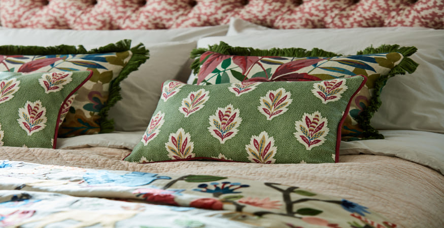 almohadones florales en tones verdes sobre una cama