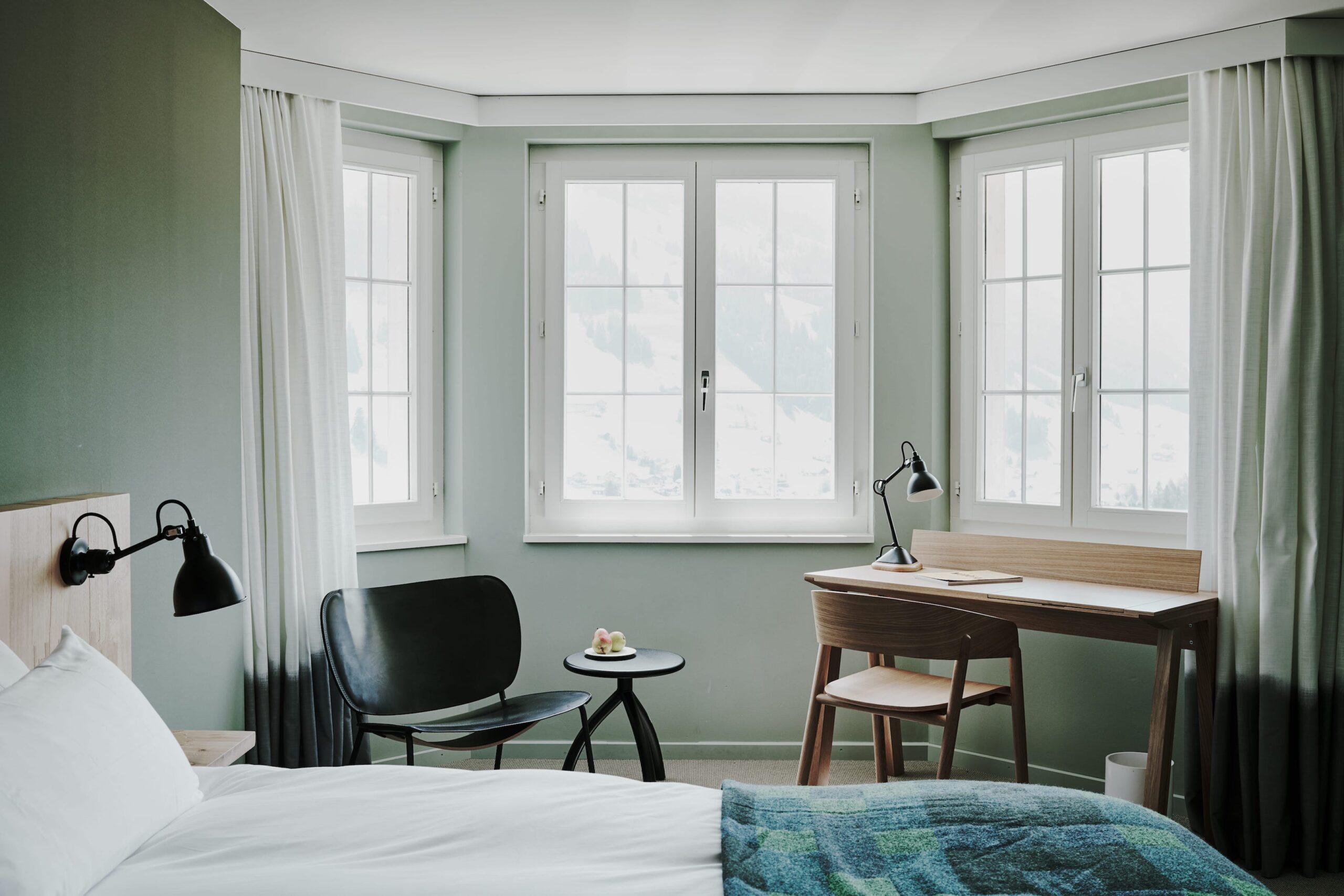 habitacion de hotel con una cama y opacantes en las ventanas con tono neutro